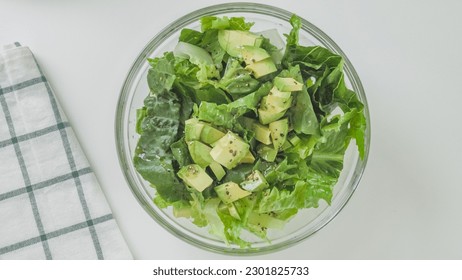 Romaine lettuce, celery, and avocado salad in a glass bowl on white kitchen table, view from above, copy space - Powered by Shutterstock