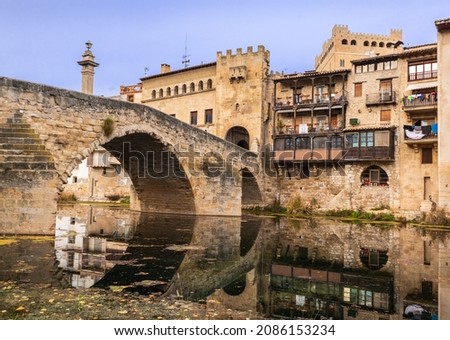 Roman bridge made of stone over the Matarraña river, medieval entrance tower to the beautiful town of Valderrobles, Teruel, Aragon, Spain