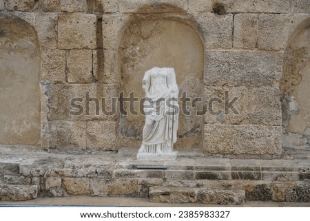 Roman goddess sculpture against arches in limestone wall