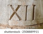 Roman numeral 12, hand carved into old hardwood timber