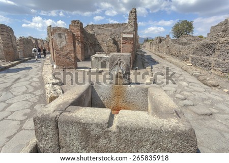 Roman ruins in Pompeii with fountain in foreground, Italy