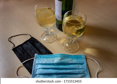 Romance Dating In Pandemic World. Two Glasses And One Bottle Of Wine With Couple Medical Masks On Table. Concept Of New Times And Lifestyle Changing Due To Lock-down Quarantine 