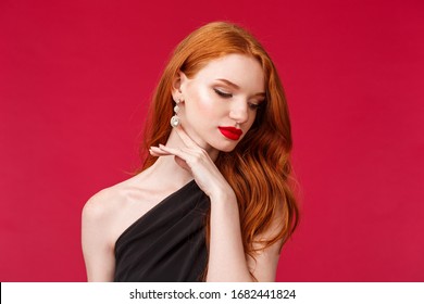 Romance, Elegance, Beauty And Women Concept. Close-up Portrait Of Seductive, Sensual And Feminine Redhead Adult Woman In Black Stylish Dress, Earrings And Makeup, Look Away Touching Gently Jawline