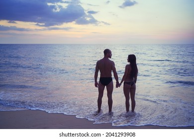 Romance On The Sea Shore. Silhouette Of A Couple In Love Holding Hands On A Sunset Tropical Background.