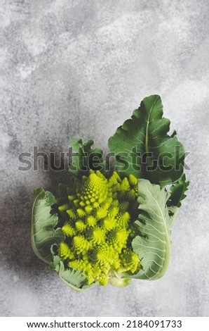 Romanesco broccoli with leaves on grey background with copy space.