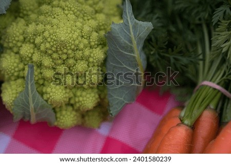 Romanesco cauliflower and carrots on a red and white checkered table cloth at a farmers market. 