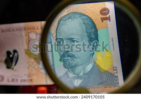 Romanian 10 LEI (RON) polymer banknote partially seen through a magnifying glass,selective focus
