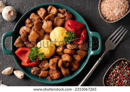 Romanian festive dish pomana porcului consisting of pieces of fried pork and sausages with pickled red peppers and corn porridge on a plate on the table. Horizontal top view.