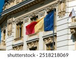 A Romanian flag waves proudly against a historic building with intricate architectural details in Sibiu, Romania.