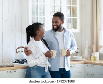 Romantic African American Spouses Drinking Coffee And Chatting In Kitchen. Cheerful Black Millennial Couple Having Hot Caffeine Drinks And Enjoying Spending Time Together At Home, Copy Space