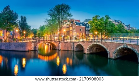 Romantic Amsterdam lit the lights. Evening panoramic view of the famous historic center with lantern lights, bridges, canals and cute Dutch houses. Amsterdam, Holland, European travel. Panoramic image