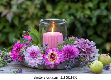 Romantic Arrangement With Pink And Purple Dahlias And Candle In Garden