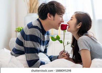 Romantic Asian couples in bedroom, a young man giving red rose to pretty woman and both kissing a beautiful rose with love and happiness,, Couple relation concept - Powered by Shutterstock