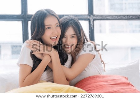 Romantic asian lgbt couple woman sitting together wake up on white bed with pillow in morning at home. Lover lesbian young girl hugging together closeness relax beside window bedroom.Relationship lgbt