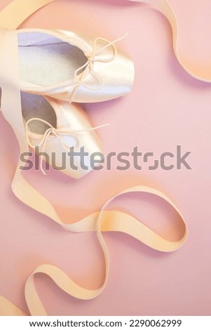 Romantic background. Pink ballet pointe shoes with ribbons on pink background. Place for text. Top view. Vertical image.