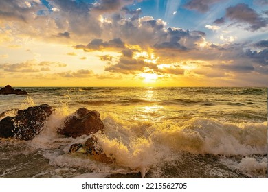 Romantic beauty of sea nature at sunset with stormy waves crashing against the coastal rocks.