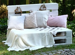 Romantic Bench Full Of Cushions In Shadowy Garden For Lovers. Bench Made From Wood Pallets  Painted With White Color. 