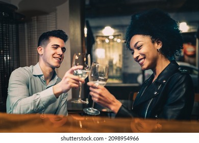 Romantic biracial couple toasting white wine sitting at restaurant - focus on the man face - Powered by Shutterstock