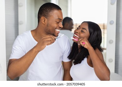 Romantic Black Couple Brushing Teeth And Smiling To Each Other In Bathroom, Happy Young African American Spouses Holding Toothbrushes, Making Morning Oral Hygiene Together, Closeup Portrait - Powered by Shutterstock