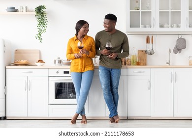 Romantic Black Couple Drinking Red Wine Together In Kitchen, Young African American Spouses Holding Glasses With Drink And Smiling To Each Other, Celebrating Valentine's Day At Home, Copy Space - Powered by Shutterstock