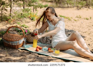Romantic blonde woman in straw hat having picnic on sea beach. Fresh fruits, juice, cookies and peaches. High quality photo - Shutterstock ID 2259171373