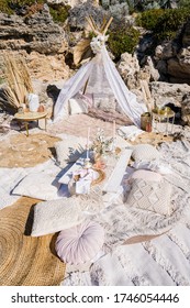 Romantic boho beach picnic setting with cushions and rugs, selective focus.