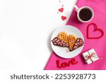 Romantic breakfast, fresh baked homemade heart shaped Belgian waffles with chocolate topping, cup of tea or coffee on white pink table. Valentines Day surprise concept. Minimalism flat lay, copy space