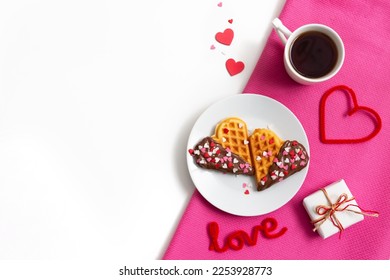 Romantic breakfast, fresh baked homemade heart shaped Belgian waffles with chocolate topping, cup of tea or coffee on white pink table. Valentines Day surprise concept. Minimalism flat lay, copy space - Shutterstock ID 2253928773