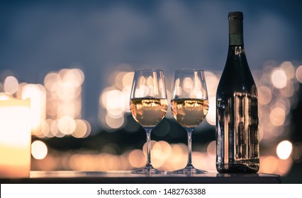 Romantic Candle Light Date Night Setting. Pair Of Wine Glasses On Table Against A Romantic City Light Background. 