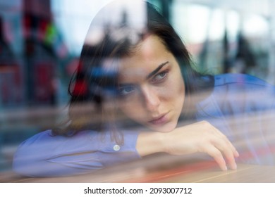Romantic casual woman portrait. Thoughtful concept. Woman at a cafe while gazing through the window glass. Sad alone girl. Beautiful girl in the window watching.