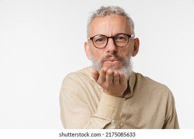 Romantic caucasian mature middle-aged man with grey hair wearing glasses sending air kisses to the camera isolated in white background. Love and relationship, passion concept - Shutterstock ID 2175085633