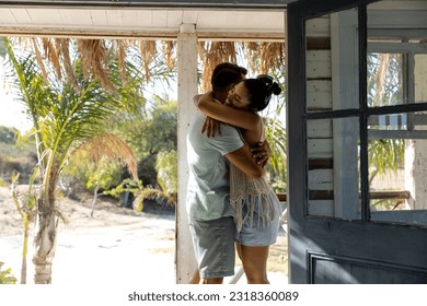 Romantic caucasian young couple embracing while standing in balcony seen through cottage doorway. Unaltered, love, together, vacation, tourist resort, lifestyle, romance and enjoyment concept. - Powered by Shutterstock