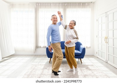 Romantic and cheerful Asian well-being senior couple enjoy dancing and holding hands to music together with smiles and happiness in the living room. Senior retirement activity at home. - Powered by Shutterstock