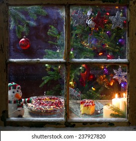 Romantic Christmas Decoration On A Window With Candles And Cake