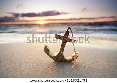 romantic colorful sunset at the sea with wooden anchor