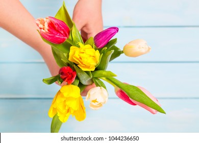 Romantic Concept. Close Up Of Colorful Tulip Flowers In Female Hands Against Light Blue Wooden Background. Colorful And Fresh Flower Bouquet. Mothersday Concept.