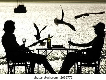 Romantic Couple Alfresco dining at cafe in nice relationship featuring silhouette by seaside drinking wine over lunch on sunset having a bit of adult peaceful alone time out and drinking wine
 - Powered by Shutterstock