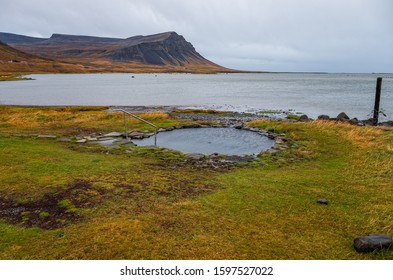 Romantic couple bathing- enjoying and relaxing in geothermal bath in the middle of wild nature, Iceland, Krosslaug pool at Barðastönd, Westfjords. September 2019