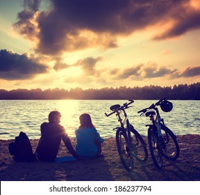 Romantic Couple with Bicycles Relaxing at Sunset. Summer Nature Background. Active Leisure Concept. Toned Photo. - Powered by Shutterstock