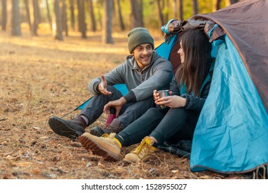 Romantic couple camping outdoors, sitting in tent, drinking tea and talking, copy space - Shutterstock ID 1528955027