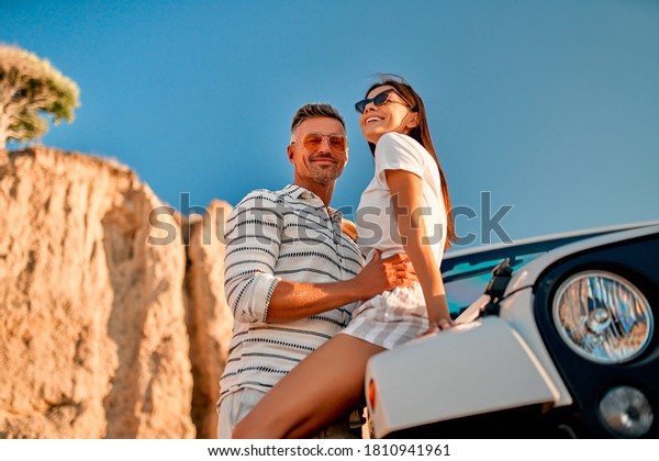 Romantic couple with car parked on
the beach. Summer vibes. Traveling together to the
sea.