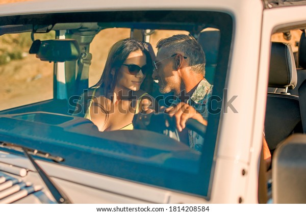 Romantic\
couple with car parked on the beach. Summer vibes. Traveling\
together to the sea. Safari on SUV\
vehicle.
