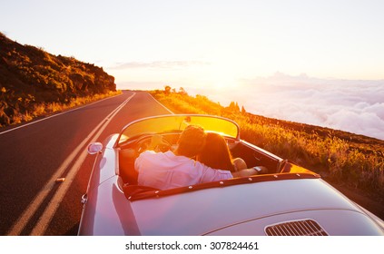 Romantic Couple Driving Into The Sunset In Classic Vintage Sports Car