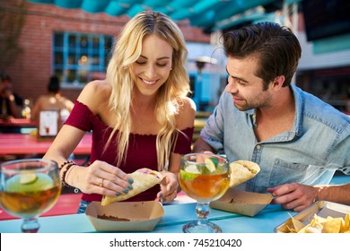 romantic couple eating street tacos at outdoor mexican restaurant - Shutterstock ID 745210420