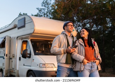 Romantic Couple Embracing Each Other While Standing At The Nature. Warm Clothes On, Autumn Time. In Background Forest And Car