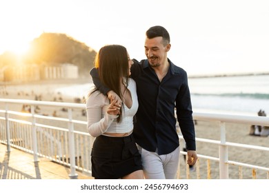 Romantic couple embracing looking at each other walking along a promenade during sunset - Powered by Shutterstock