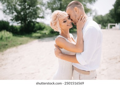 A romantic couple embracing outdoors in the sunlight, dressed in white clothing. They are standing close, radiating love and affection. - Powered by Shutterstock