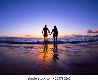 Romantic couple enjoying a beach walk at sunset