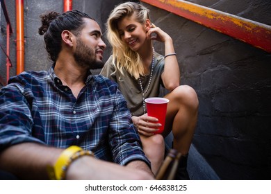 Romantic couple enjoying while having drink on staircase of bar - Powered by Shutterstock