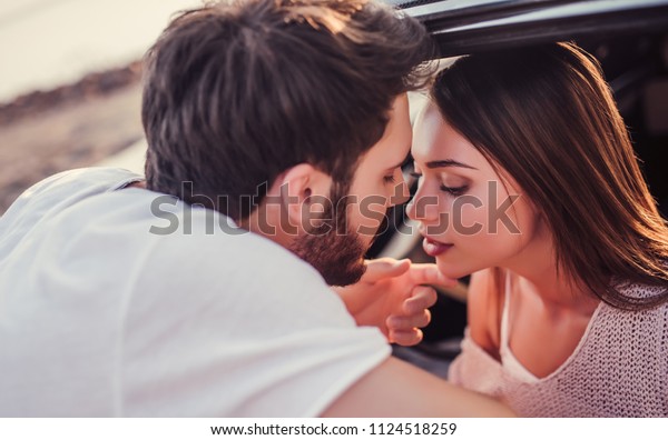 Romantic couple with green retro car on the\
beach.Handsome bearded man and attractive young woman with muscle\
car.Stylish girl is sitting in car while her man is standing near\
and kiss her. Love\
story